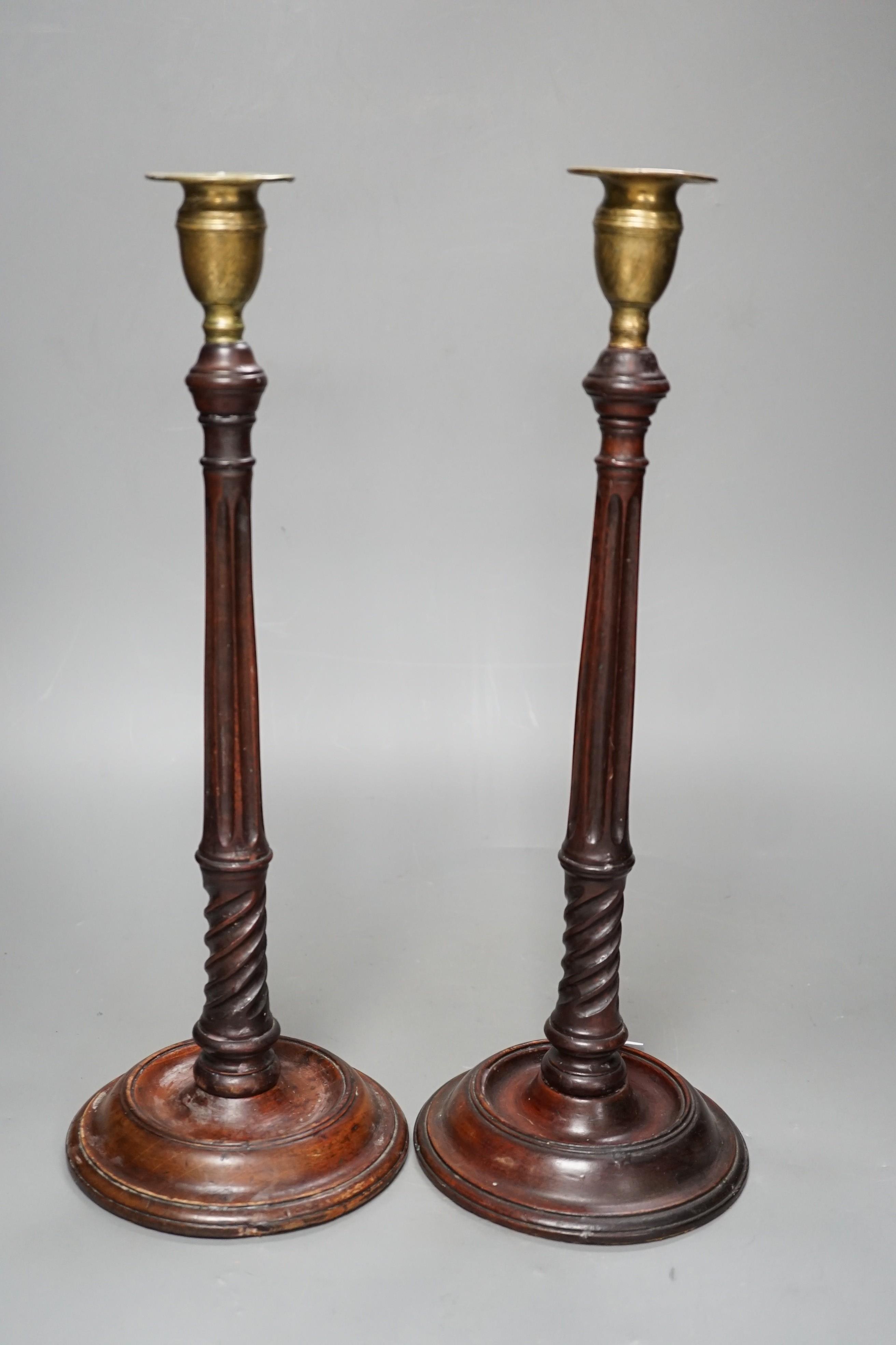 A pair of George III style carved mahogany candlesticks, with brass sconces, 38cms high